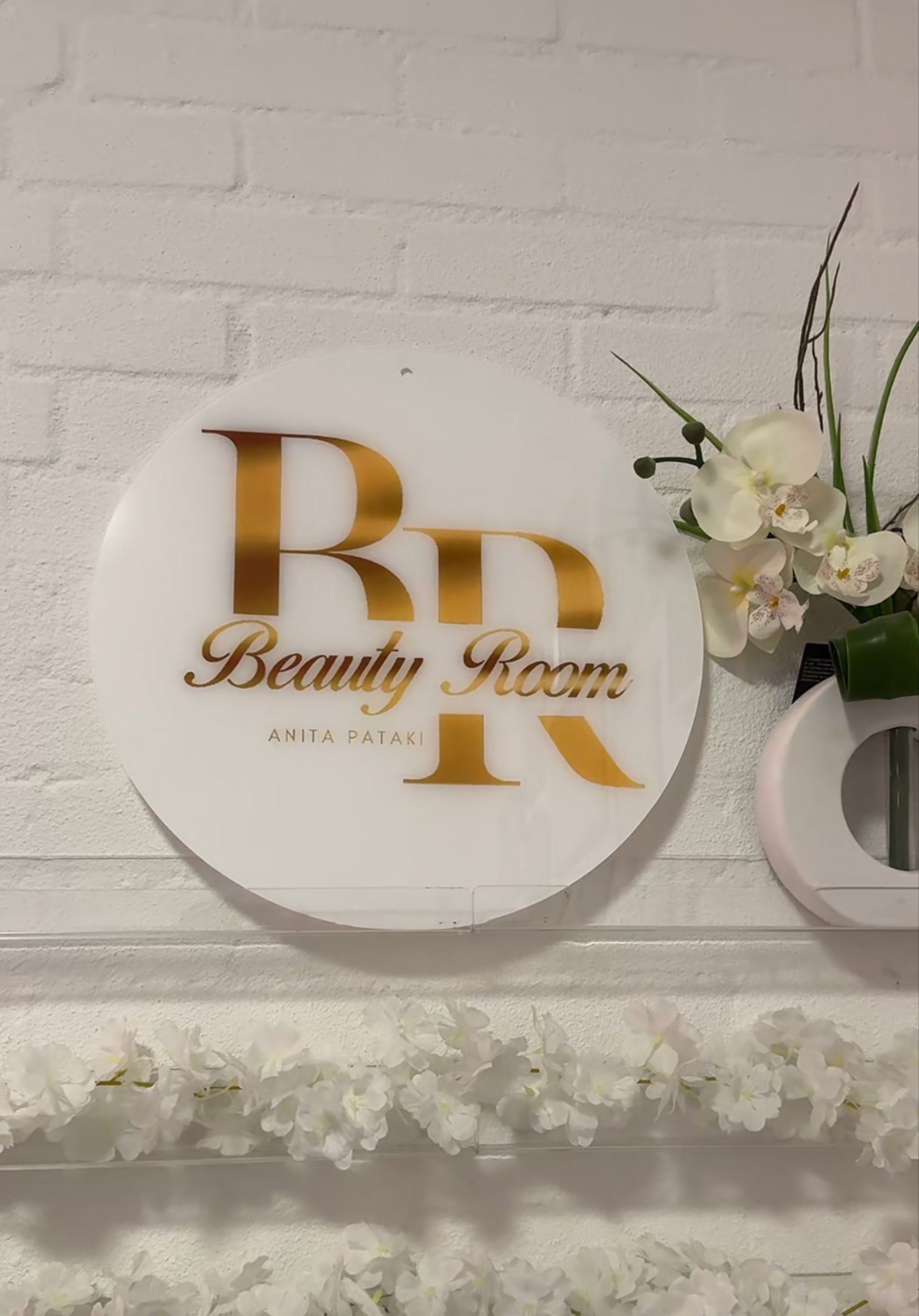 Het gouden Beauty Room logo aan de muur van de studio